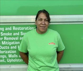 Female employee with black SERVPRO shirt smiling in front of a green background