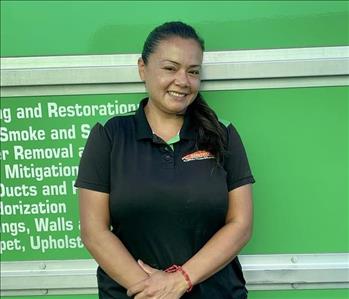 Female employee with dark hair smiling in front of a green background