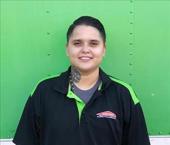 Female SERVPRO employee with short hair smiling in front of a green background